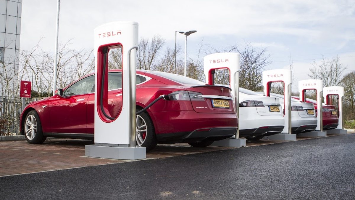A red Tesla Model S charging at a row of Tesla Superchargers in the UAE
